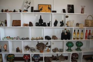 Display of the many art types including B&W sand portrait (top shelf), wood and volcanic rock carvings.